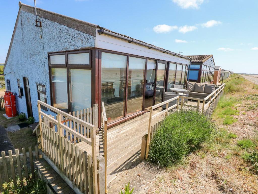 a house with a wooden porch and a deck at 102 The Beach in Snettisham