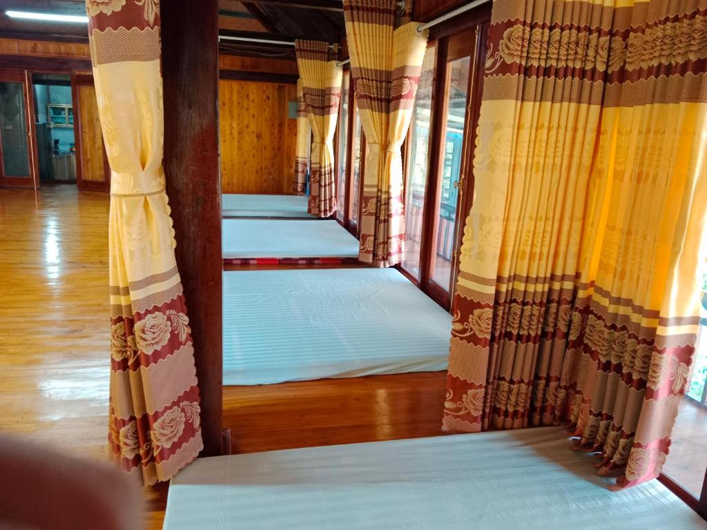 a row of white mattresses in a room with curtains at homestay phô núi suôi giang in Yên Bái