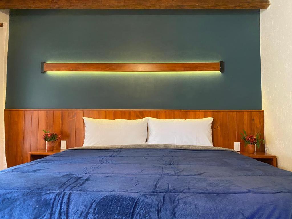 a blue wall with a bed with white pillows at Hotel Muk´ul Na in San Cristóbal de Las Casas