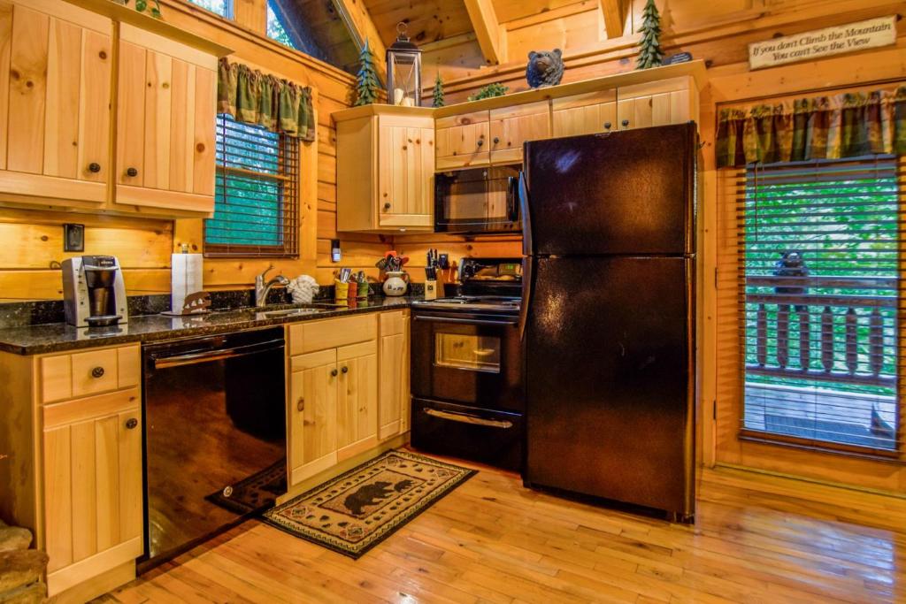 une cuisine avec un réfrigérateur noir et des armoires en bois dans l'établissement Beary Cozy Cabin, à Sevierville