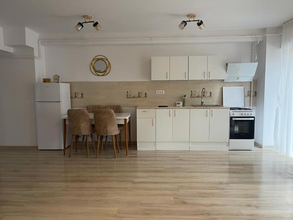 a kitchen with white cabinets and a table and chairs at Apartament YRA Rm.Valcea in Râmnicu Vâlcea