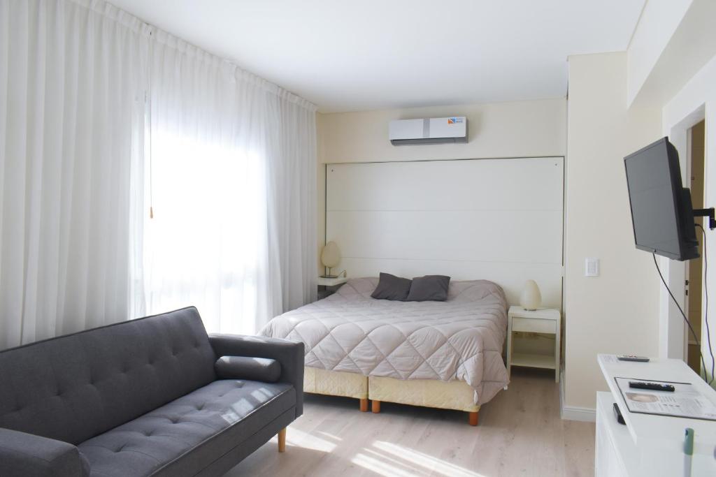 - une chambre avec un lit, un canapé et une télévision dans l'établissement Syrah Studios, à Buenos Aires