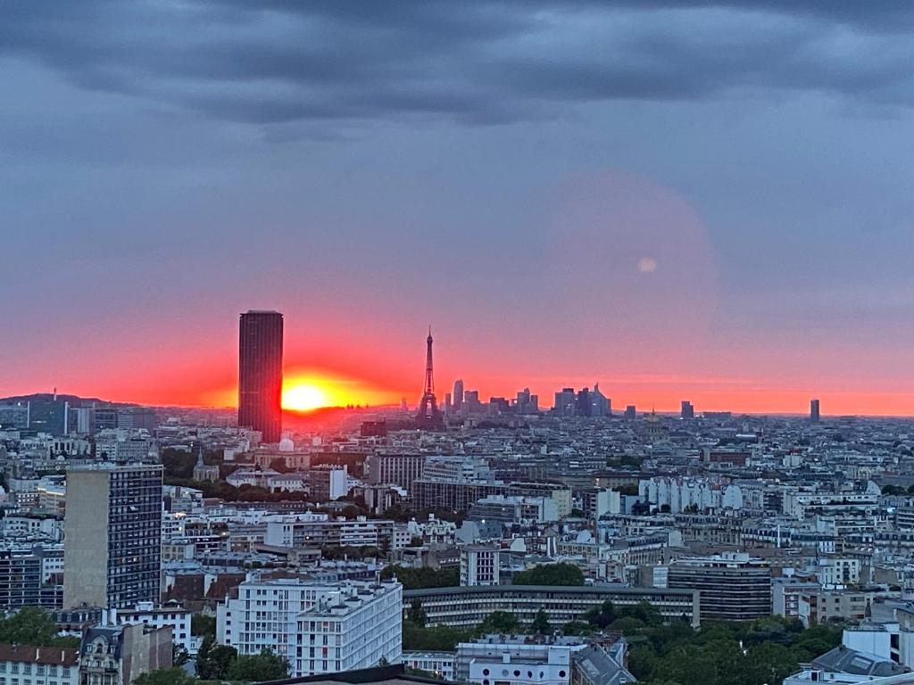 Un horizonte de ciudad con el sol poniéndose en el cielo en Grand appartement luxueux, calme et sûr, en París