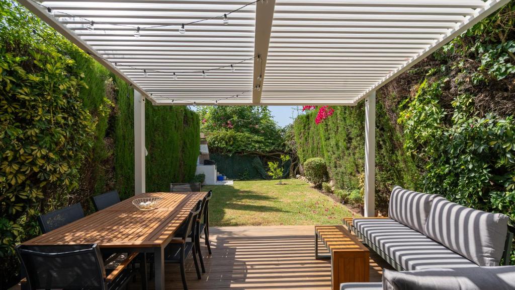 eine Terrasse mit einem Holztisch und Stühlen in der Unterkunft Luxury townhouse capricho golden mile in Marbella