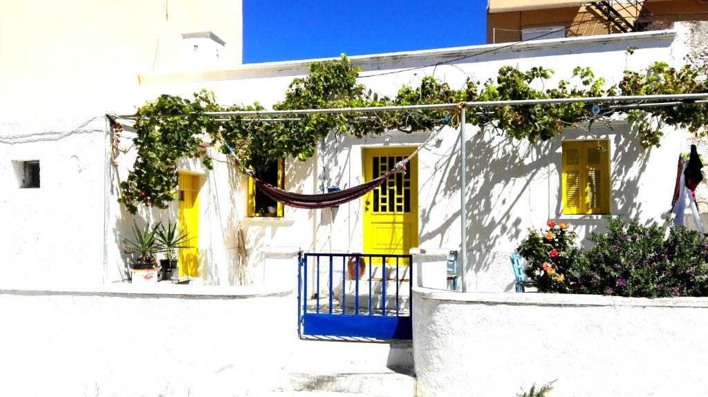a white house with yellow doors and a hammock in front at Artist Rooms - Triantafyllou Birth House in Kefalos