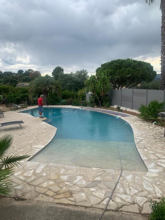 Ein Mann steht neben einem großen Schwimmbad. in der Unterkunft Petit endroit paisible in La Roquette-sur-Siagne