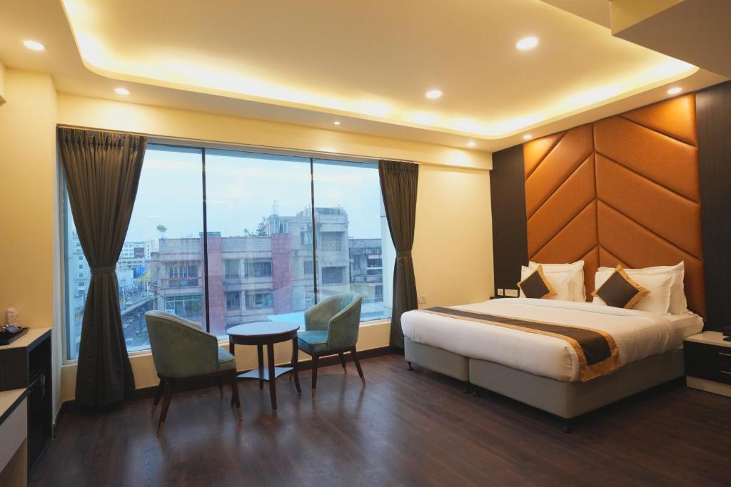 a hotel room with a bed and a large window at Hotel CP Palace in Patna