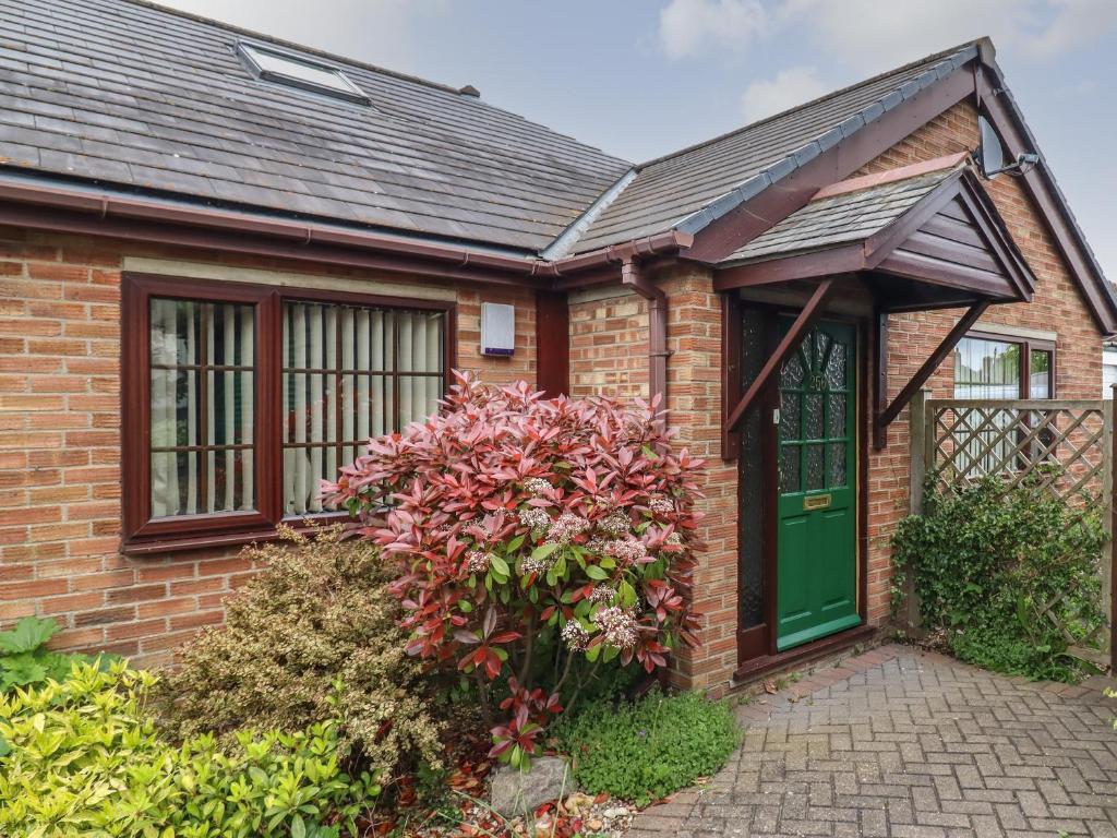 una casa de ladrillo con una puerta verde y flores en 256 London Road en Colchester