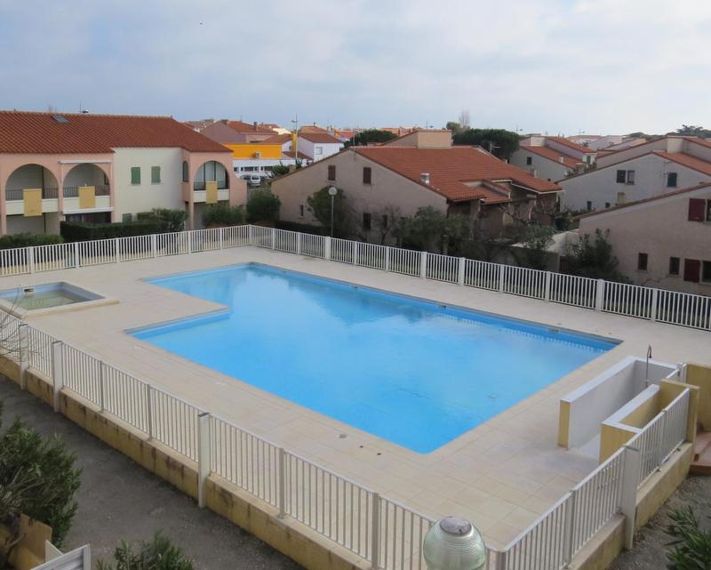 - une grande piscine bleue dans une cour avec des maisons dans l'établissement appartement 5 personnes résidence piscine 5PB274, au Barcarès