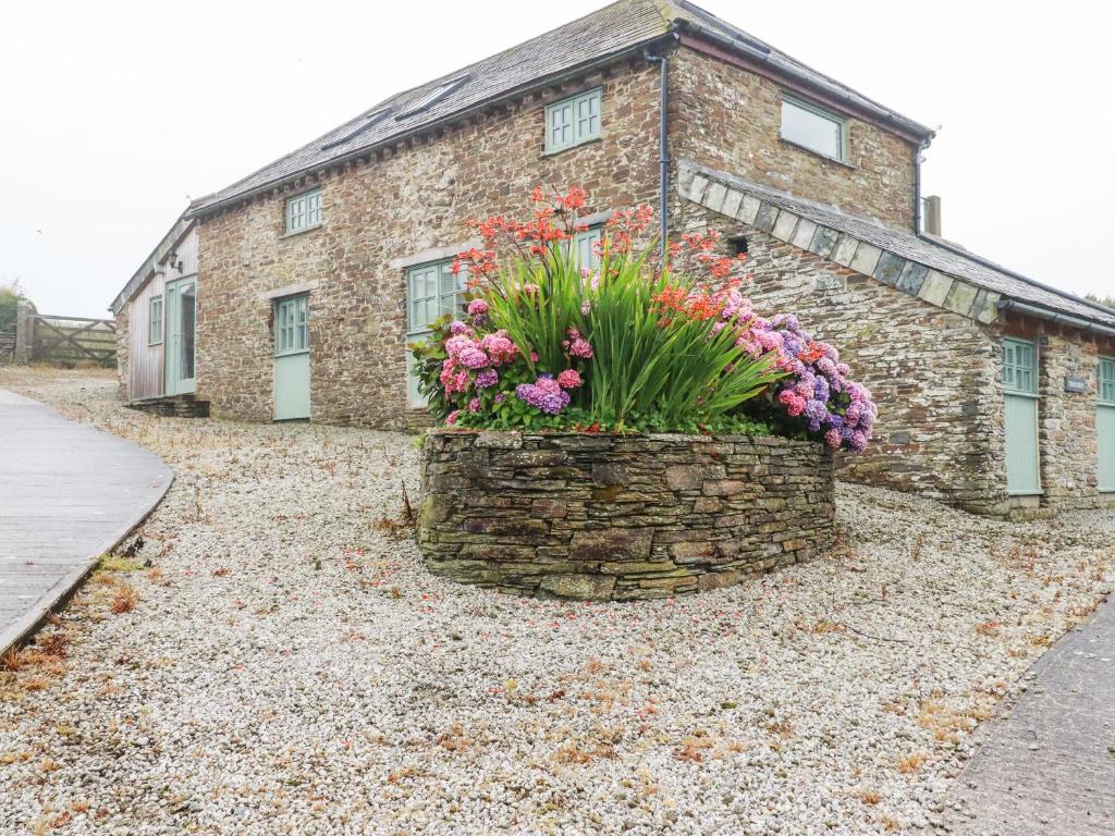 a brick building with flowers in a stone wall at Trerubies in Delabole