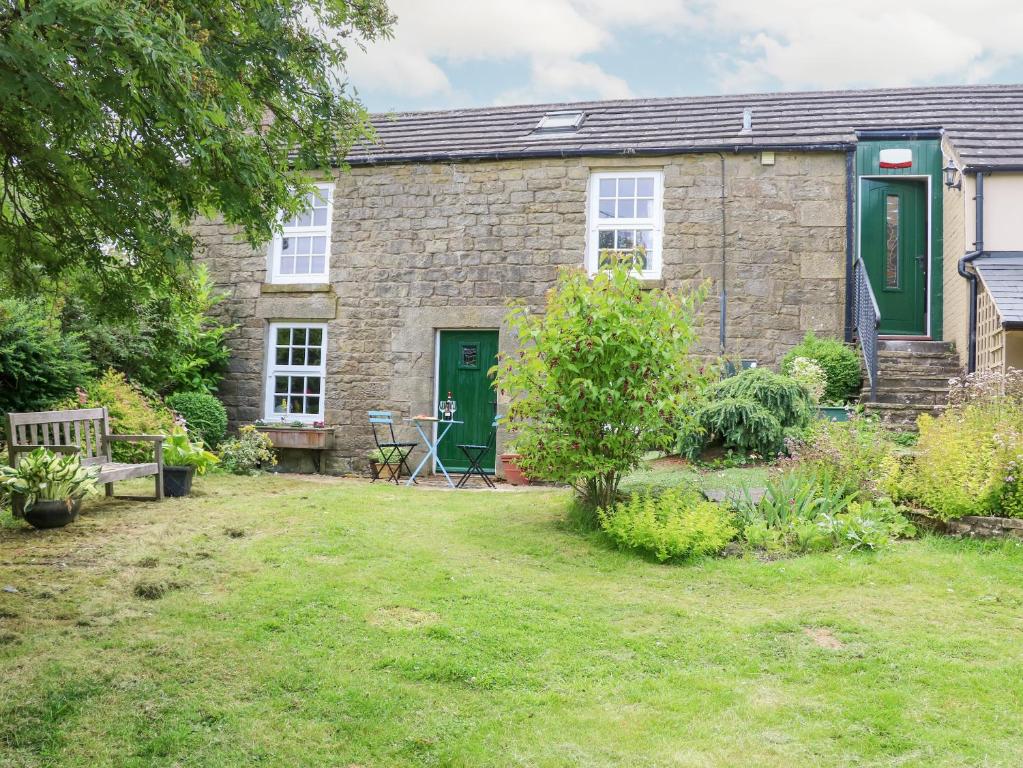 a stone house with a green door and a yard at Hepple Hill Cottage in Consett