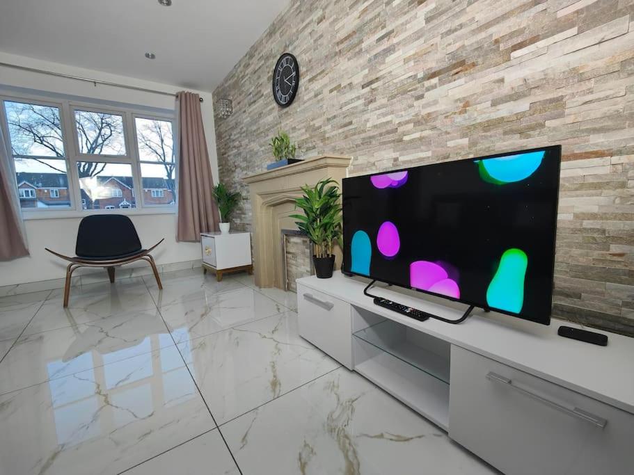 uma sala de estar com uma televisão de ecrã plano e uma lareira em Tyburn Home, Birmingham with FREE Parking em Birmingham