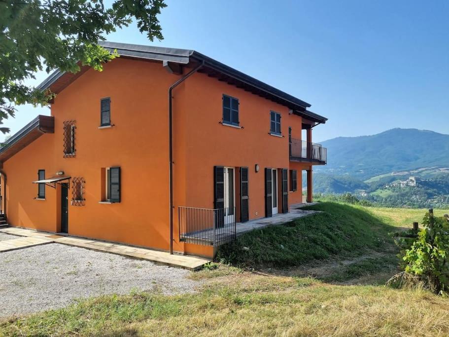 uma casa laranja numa colina com montanhas ao fundo em Oasi di pace nella Val di Taro em Compiano