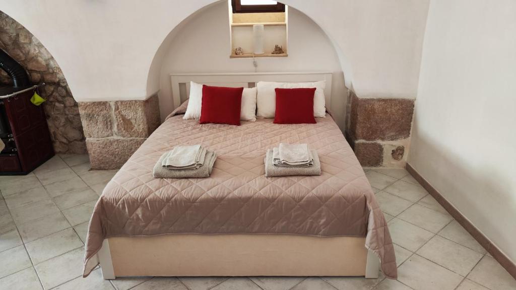 La Locanda di Nonno Paolo في ألتامورا: غرفة نوم بسرير كبير ومخدات حمراء