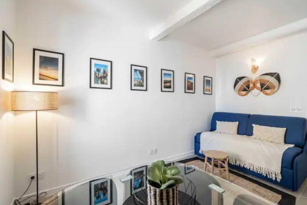 a bedroom with a blue couch and pictures on the wall at Chez Jude in Cannes