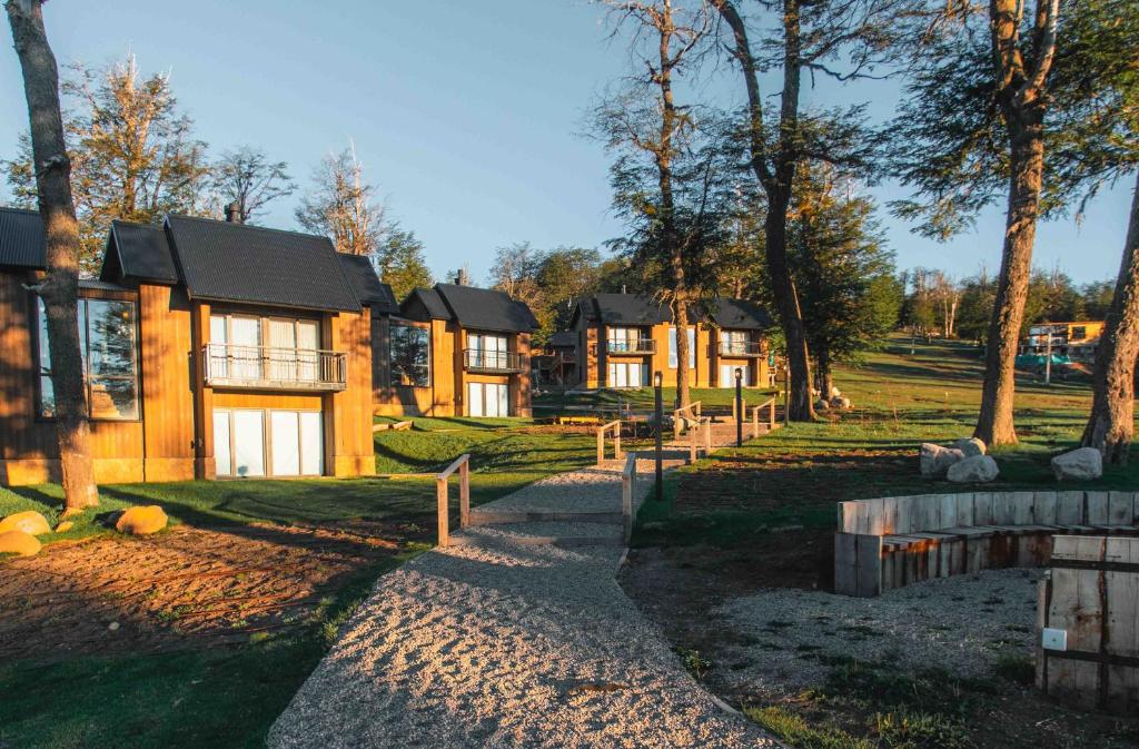 una fila de casas en un parque con árboles en El Refugio Ski & Summer Lodge en San Martín de los Andes