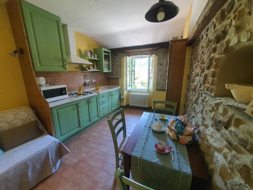 una cocina con armarios verdes y una mesa en una habitación en Da Nonna Mafalda near 5 terre, en Brugnato