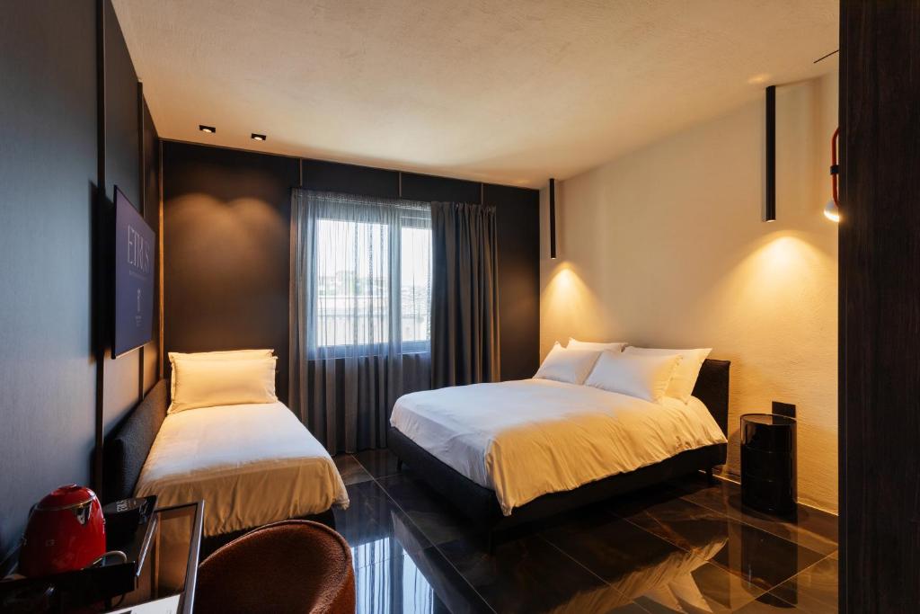a hotel room with two beds and a window at Etrus - Boutique Room & Rooftop in Pontecagnano