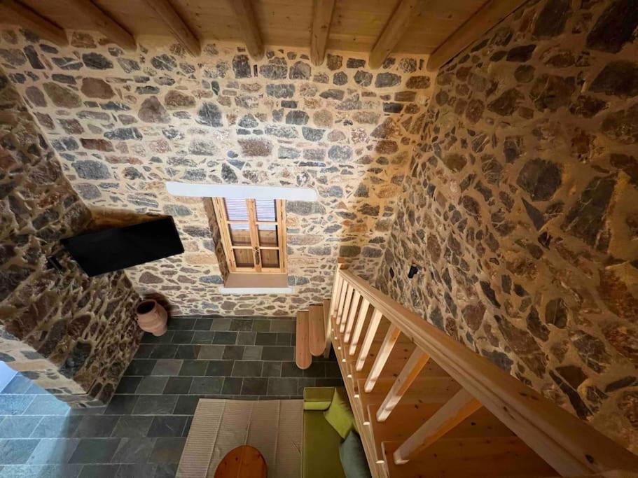 Habitación con pared de piedra, ventana y escaleras. en Luxury Historic Island Home with Private Garden, en Poros