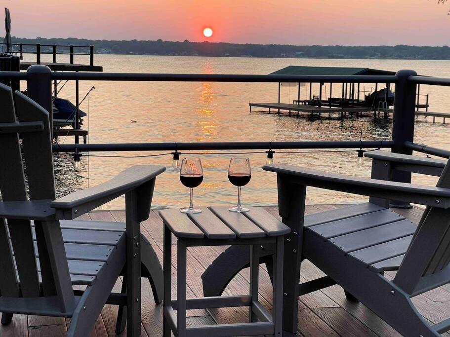 two glasses of wine sitting on a table near the water at Luxurious, Tranquil, 4BR Lakefront Villa in Mabank