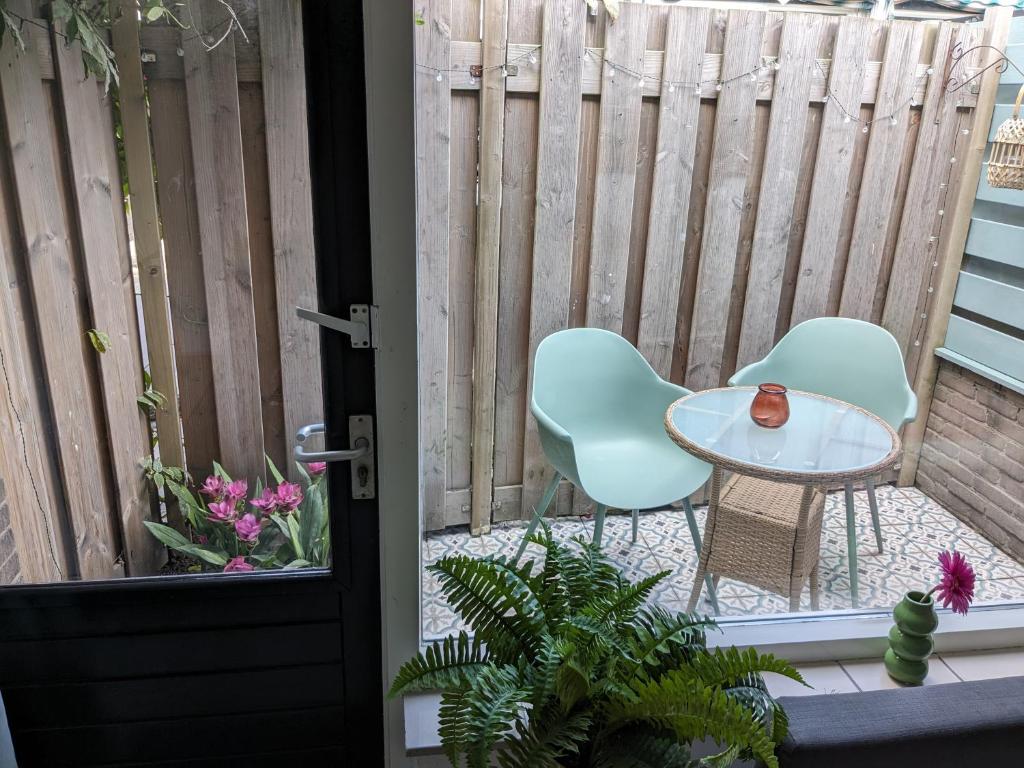 een patio met 2 stoelen, een tafel en een hek bij zomerhuis in Wijk aan Zee! 2 pers in Wijk aan Zee