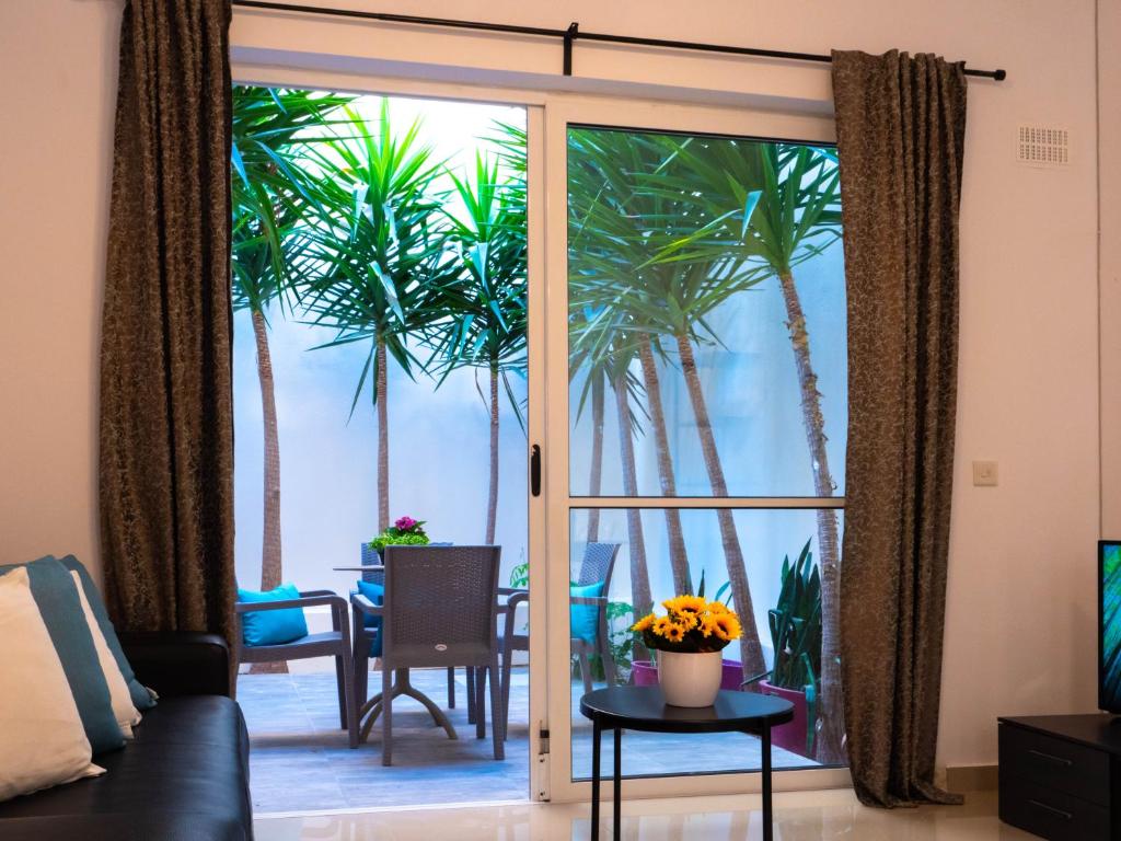 ein Wohnzimmer mit einer Glasschiebetür mit Palmen in der Unterkunft CityScape Gzira Holiday Apartments and Penthouses By ShortletsMalta in Gżira