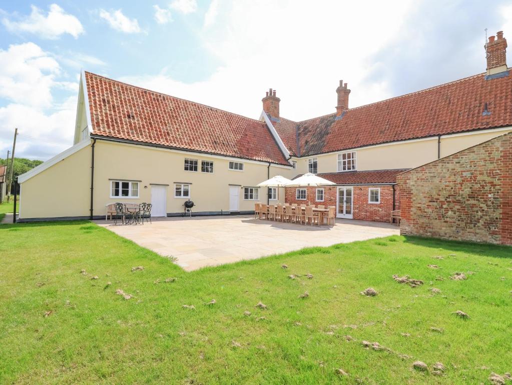 an external view of a large brick building with a patio at South Grange Cottage in Saxmundham