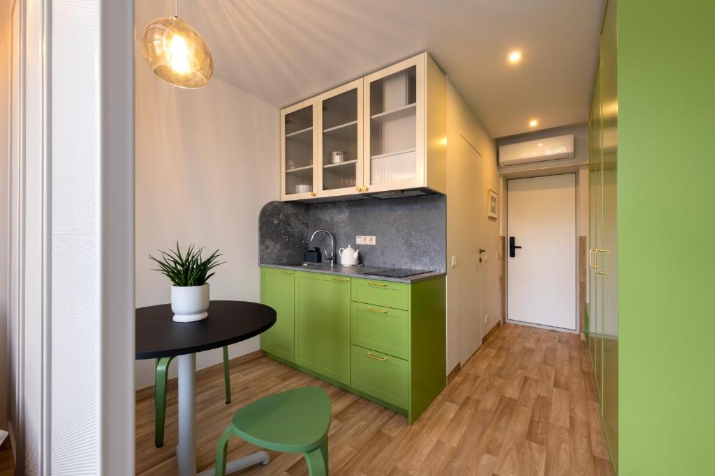 a kitchen with green cabinets and a table and chair at Berlin Studios in Klaipėda