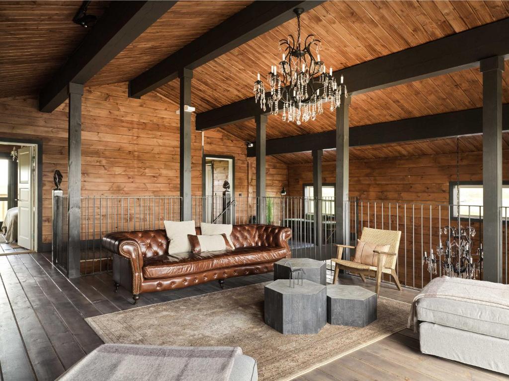 a living room with a leather couch and a chandelier at Laxá Lodge in Hella