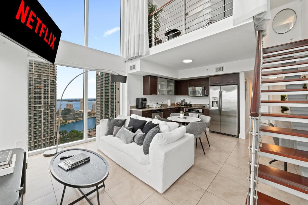 a living room with a white couch and a kitchen at Skyline Serenity - Brickell On The River 1901 - Bi-Level Loft with Breathtaking Views On The Ocean in Miami