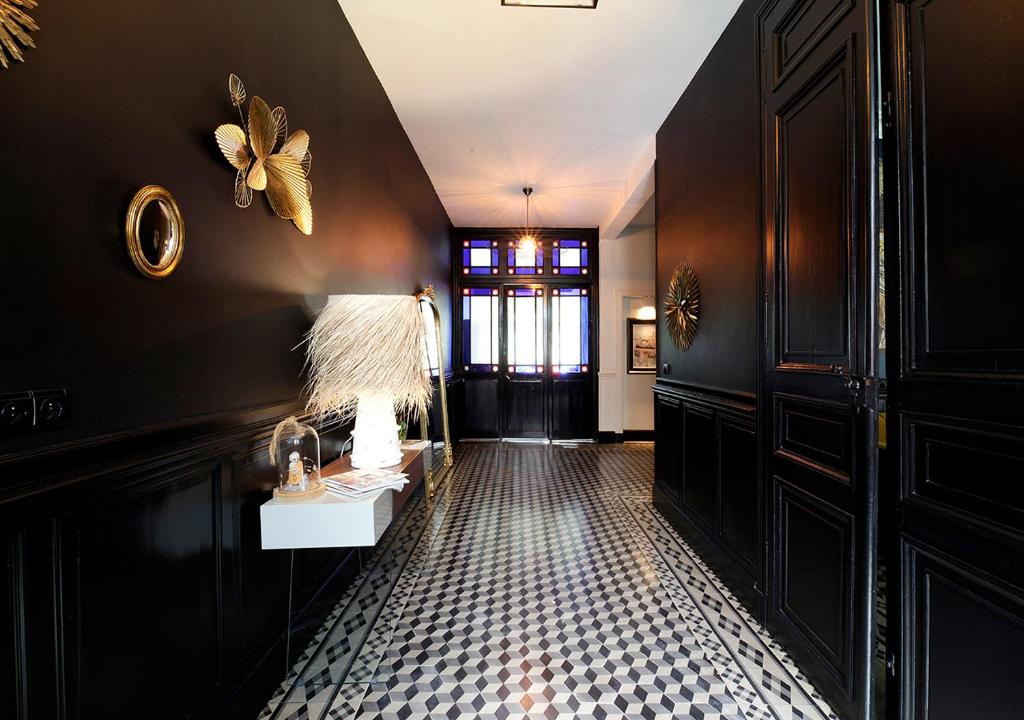 un couloir aux murs noirs et une table avec une lampe dans l'établissement Maison d'Hôtes " L'INSTANT D'AILLEURS", à Albi