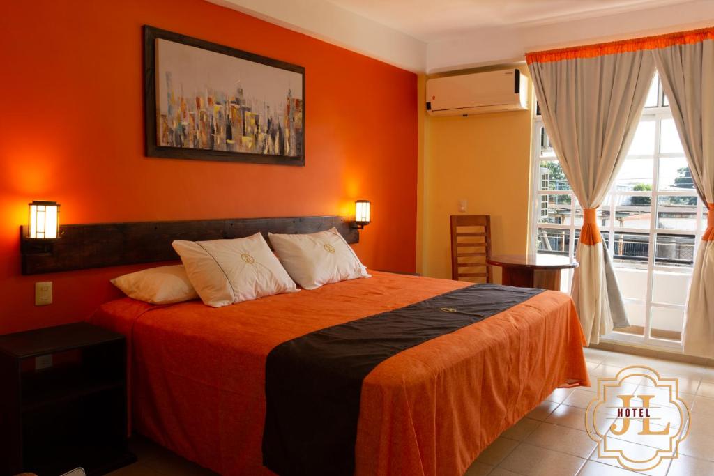 Hotel JL في Tierra Blanca: غرفة نوم مع سرير بجدران برتقالية ونافذة
