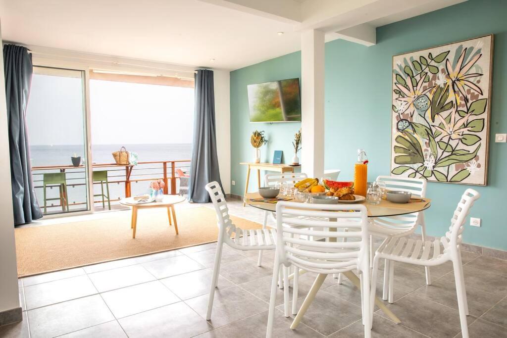a dining room with a table and chairs with a view of the ocean at Ti soleil, appartement 3 pièces neuf, front de mer in Les Anses-dʼArlets