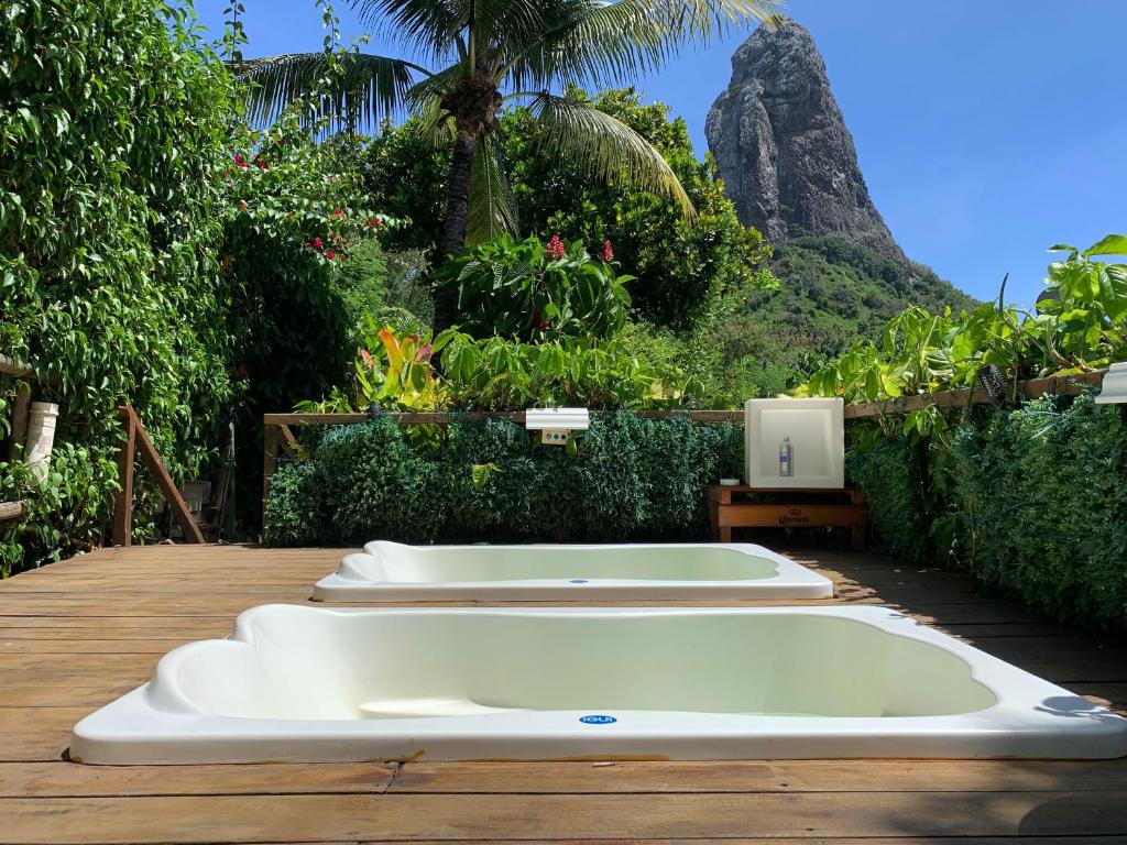 3 lavabos blancos sobre una mesa de madera con una montaña en Villa na Praia em Fernando de Noronha, en Praia da Conceição