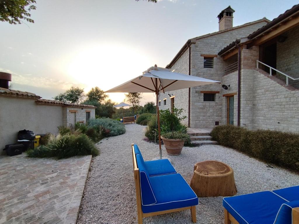 un patio con una silla azul y una sombrilla en Agriturismo Montecolombo by Il Ritorno, en Massignano