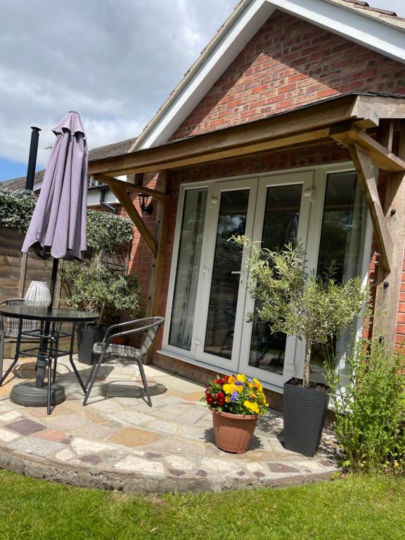 eine Terrasse mit Tisch und Sonnenschirm in der Unterkunft Chestnut Cottage in East Bergholt