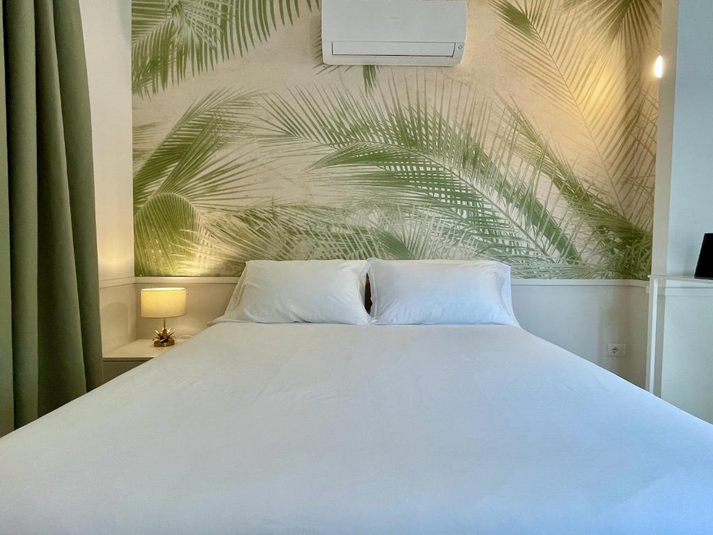 a bedroom with a white bed and a palm tree mural at Forte 01 in Forte dei Marmi