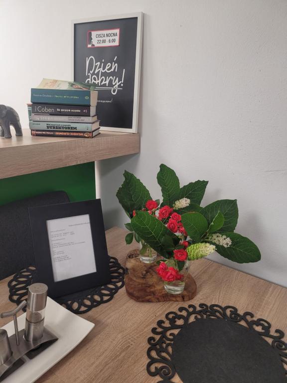 ein Schreibtisch mit einer Blumenvase und einem Tablet in der Unterkunft Pokoje na Warszawskiej in Gorzów Wielkopolski