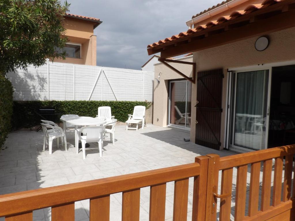 un patio avec une table et des chaises sur une terrasse dans l'établissement Les logis de Magali Les Acacias, maison, clim, parking, à Argelès-sur-Mer