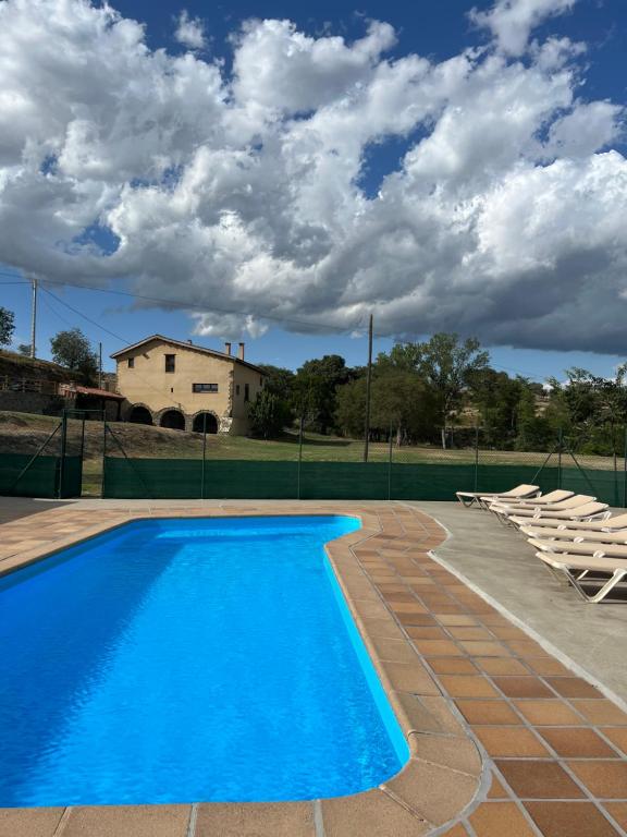 een zwembad met stoelen en een huis op de achtergrond bij Casa Vella del Cuní in Roda del Ter