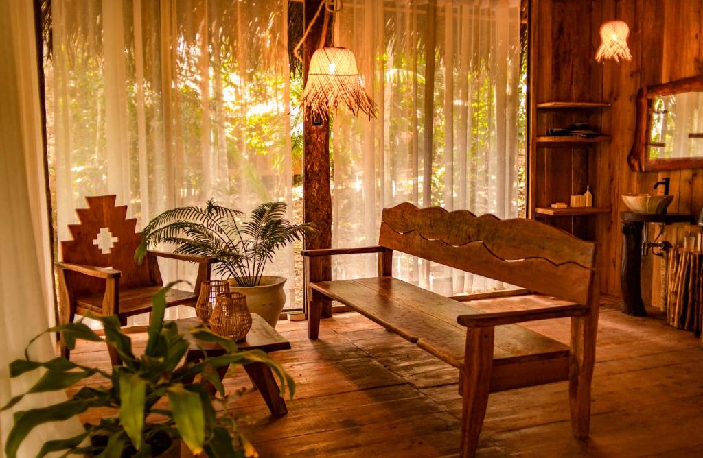 Habitación con banco y ventana con cortinas. en AWAKEN Amazonian Healing Resort ALL INCLUSIVE, en Iquitos