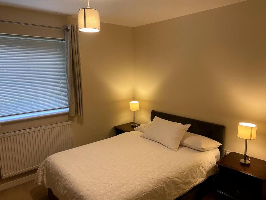 a bedroom with a bed with two lamps and a window at Spacious Ground Floor Flat in Buckinghamshire