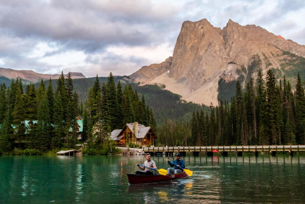 2 personnes dans un bateau sur un lac avec une montagne dans l'établissement Emerald Lake Lodge, à Field