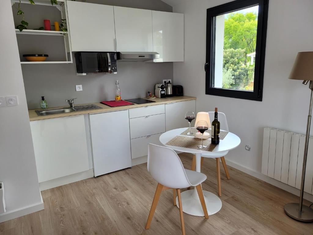 a kitchen with white cabinets and a table and a window at cosy, spacieux, avec balcon, au calme in Artigues-près-Bordeaux