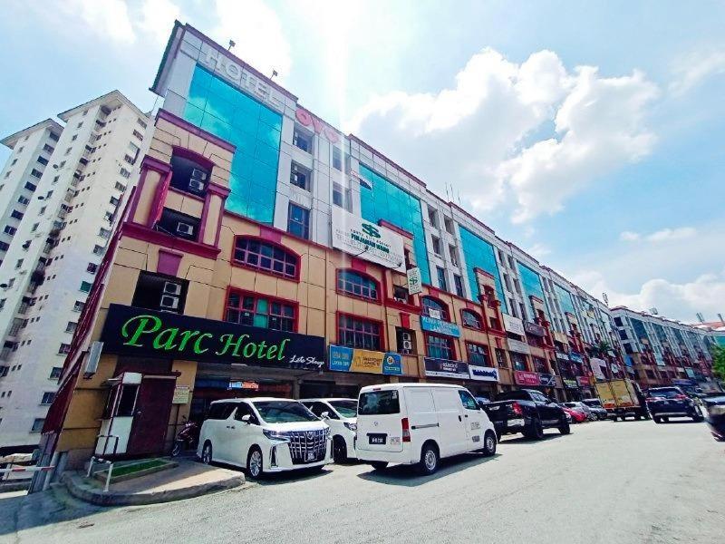 ein großes Gebäude mit Autos auf einem Parkplatz in der Unterkunft Parc Hotel Pelangi Damansara in Kota Damansara