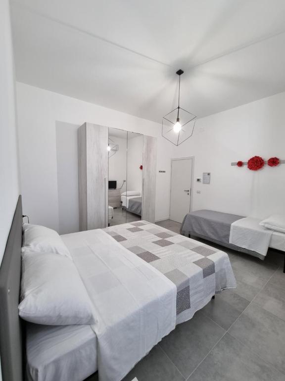 a white bedroom with two beds and a mirror at CASA VERDi 37 CAMERA RUBINO SMERALDO in Porto SantʼElpidio