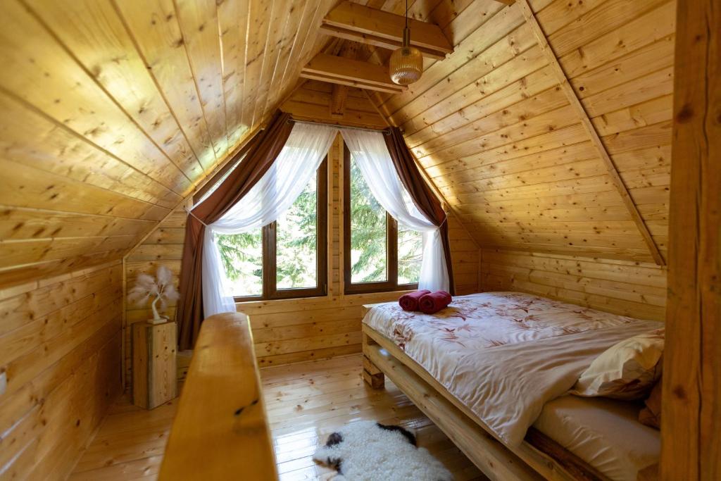 a bedroom in a log cabin with a bed and a window at Pura Vida Forest Home in Poiana Horea