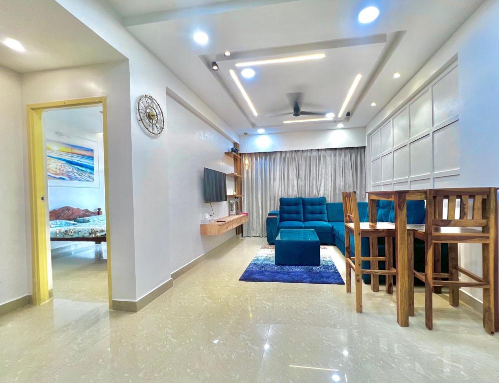 a living room with blue chairs and a dining room at Coco Loco Colva in Colva