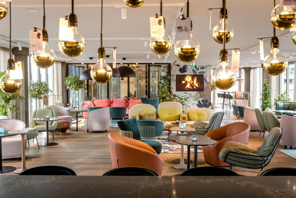 a lobby with chairs and tables and chandeliers at Motel One Rotterdam in Rotterdam