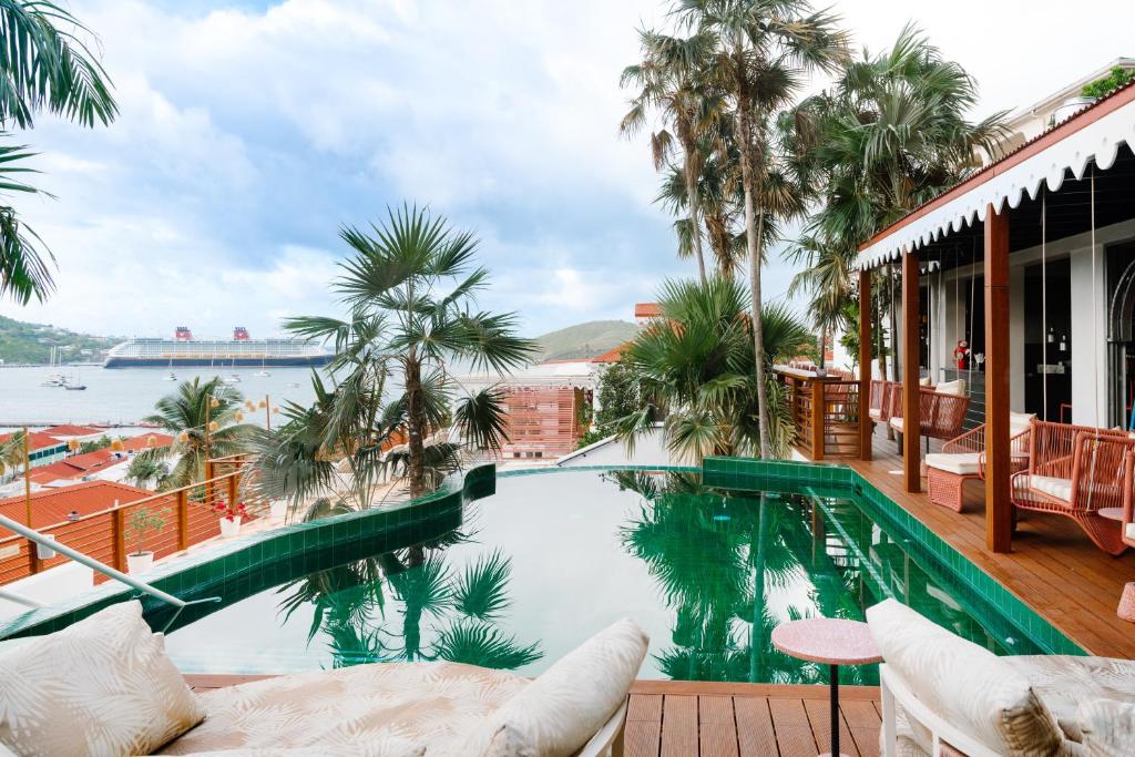 uma piscina com palmeiras e vista para a água em The Pink Palm Hotel - Adults Only em Charlotte Amalie